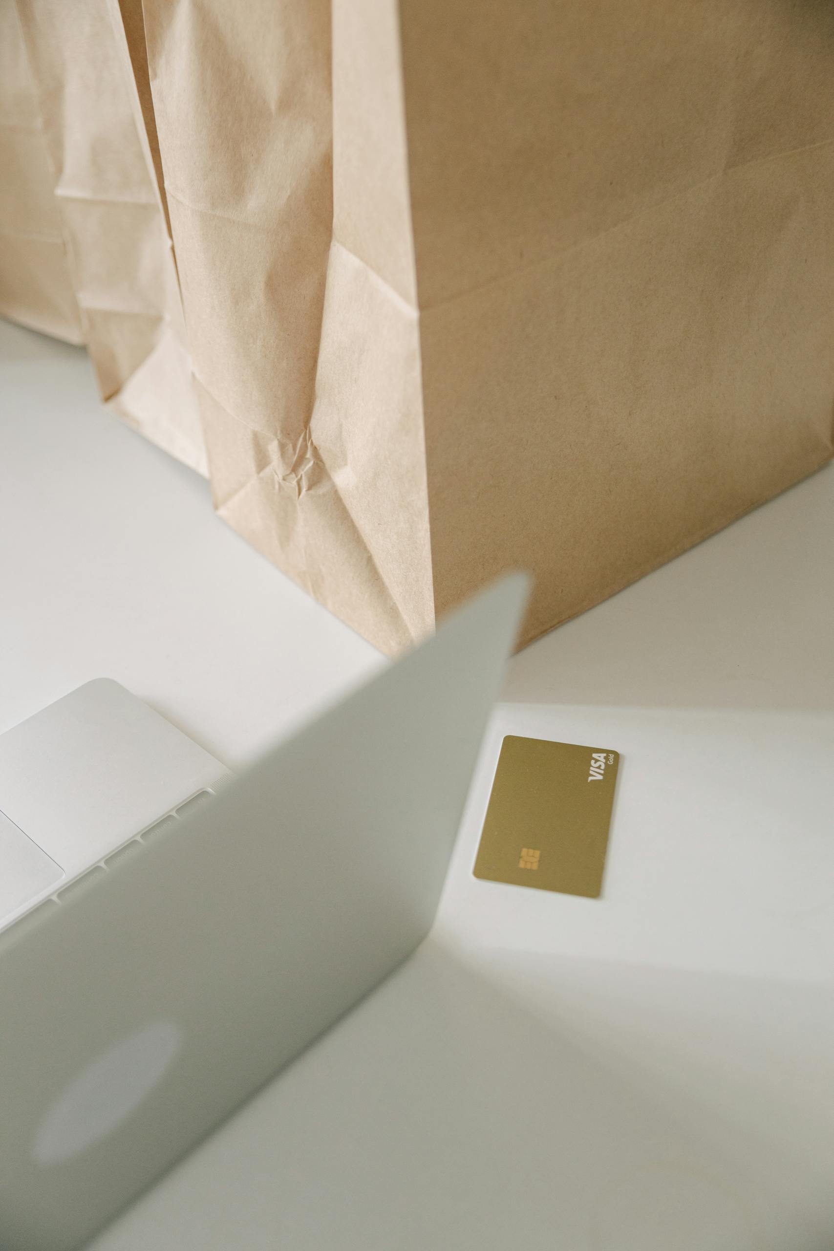 A minimalist setup featuring a laptop, shopping bag, and credit card representing online shopping and e-commerce.